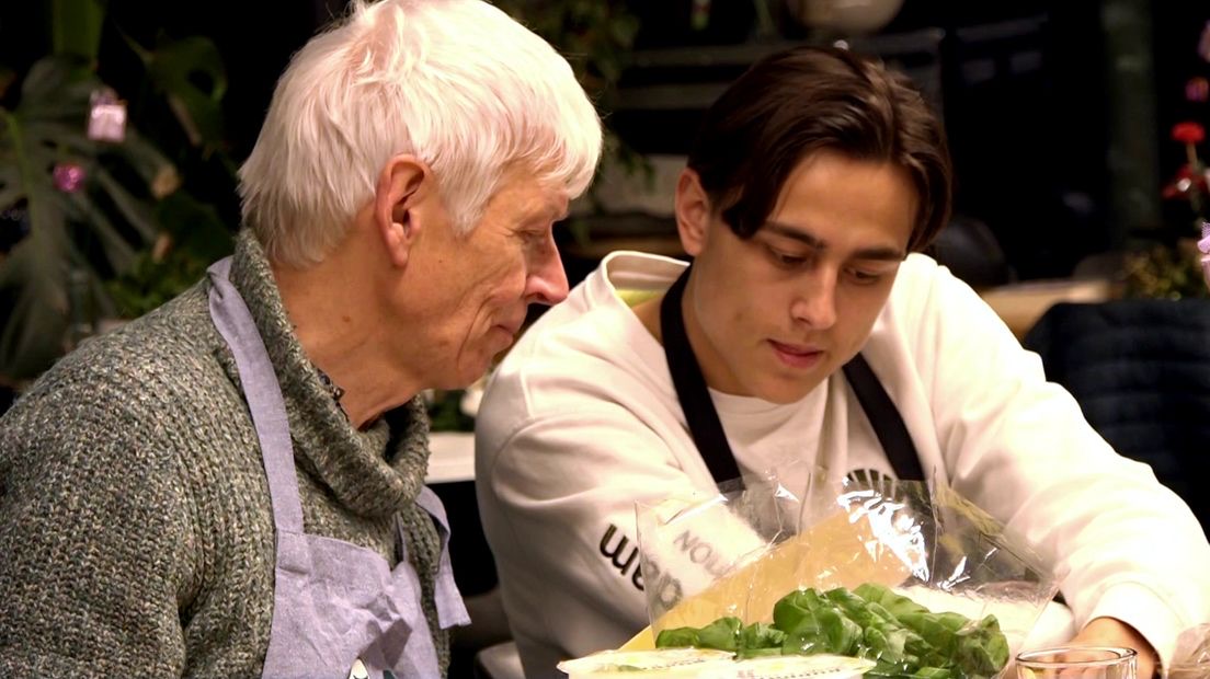 Een student en oudere man koken samen tijdens een kookavond